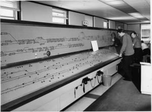 Black and white photo of two men standing at an early computer