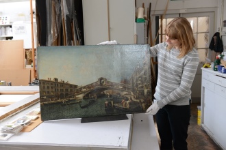 Photo of a conservator holding the rialto bridge painting