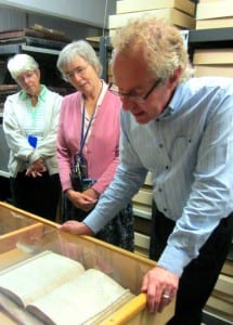 image of three people looking at an archival document of a burial register