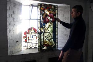 Photo of a conservator assessing a stained glass window