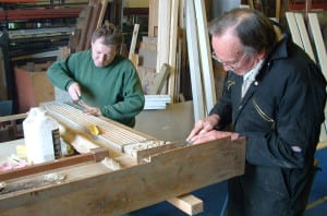 Two men in overalls planing some wood