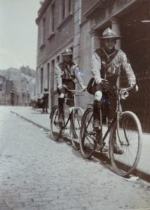 Two children riding bicycles in the street outside the Guild of the Brave Poor Things