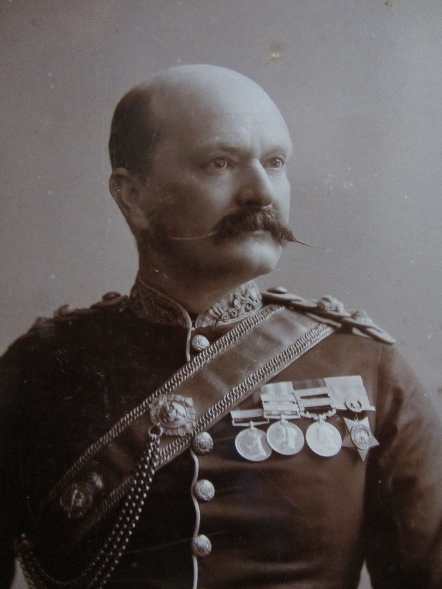 Old fashioned image of a bald man, with a large mustache and dressed in military uniform.