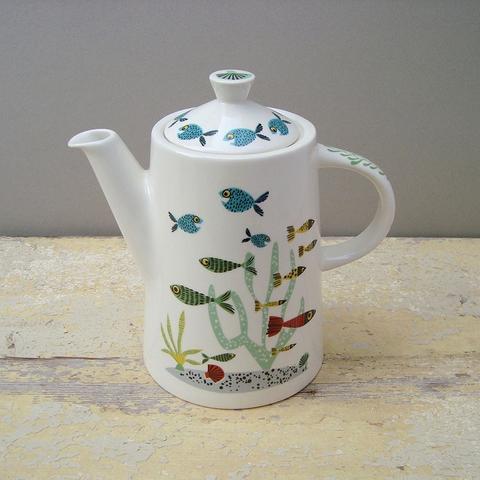 a white teapot decorated in a colourful fish design