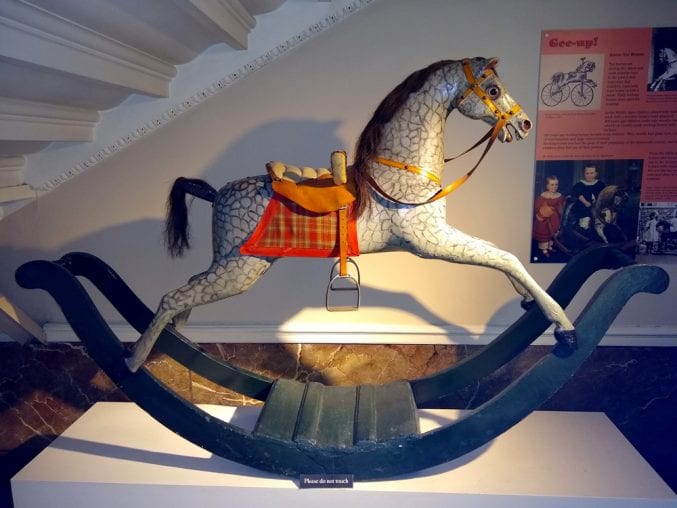 Photo of the rocking horse on display under a staircase at blaise castle house museum