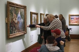 A picture taken from a Dementia friendly creative cafe - a group of people looking at a painting in the French gallery