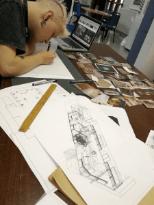 Marcin working next to a 3D sketch of the gallery design