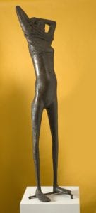 A standing female human figure removing her clothes, cast in bronze by Reg Butler