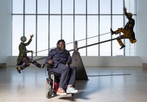 Yinka Shonibare sat in front of "End of Empire" at Turner Contemporary