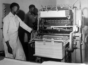 Two men check newspaper printing press