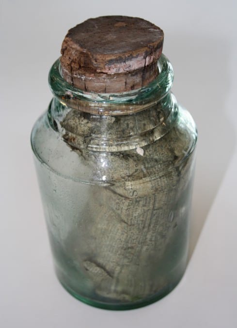 Photo of a corked glass jar with a newspaper in it