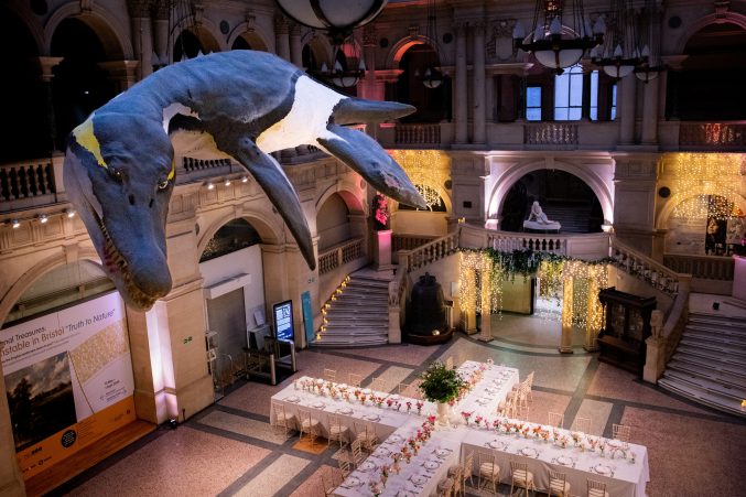 A model plesiosaur hanging over a set up wedding table in the shape of a cross