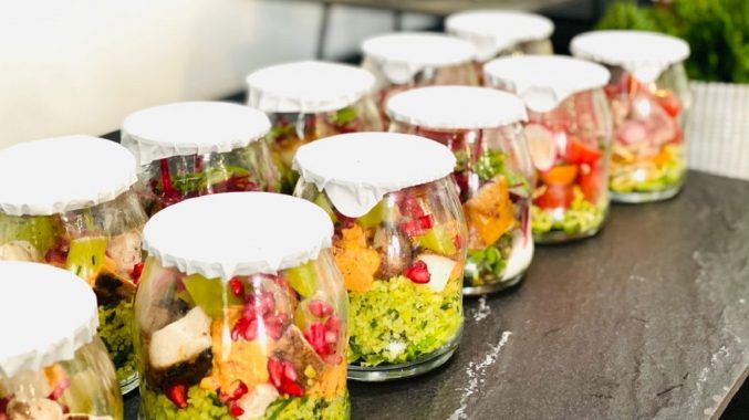 Portions of colourful food individually wrapped inside glass containers and foil lids