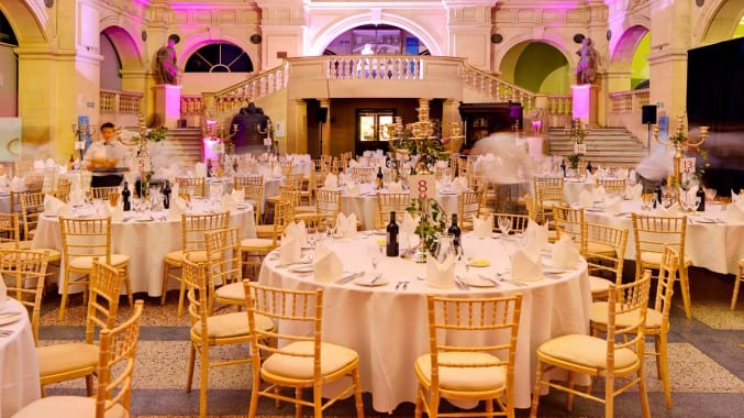 Photo of the rear hall in Bristol Museum & Art Gallery at night, with tables set up for an evening event