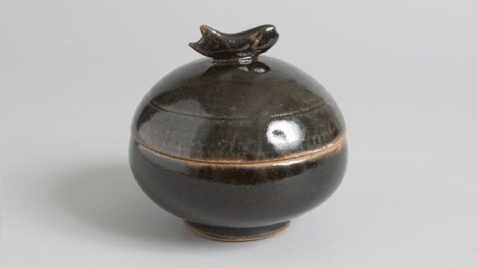 Speherical pot by Bernard Leach. Black tenmoku glaze, modelled fish handle. Brown glazed interior.