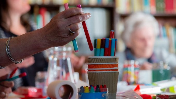 A hand reaching into a pot of colourful felt tip pens