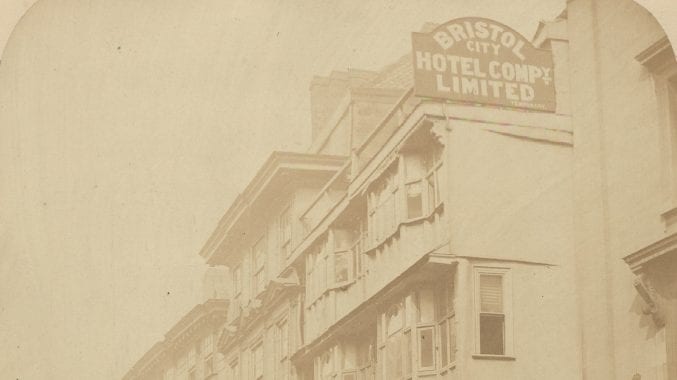 Street view of the Bristol hotel with horse and carriages and pedestrians in the foreground.