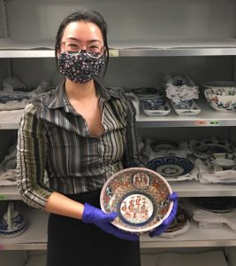Photograph of Amy, Project Curator, holding a porcelain bowl. The bowl is beau