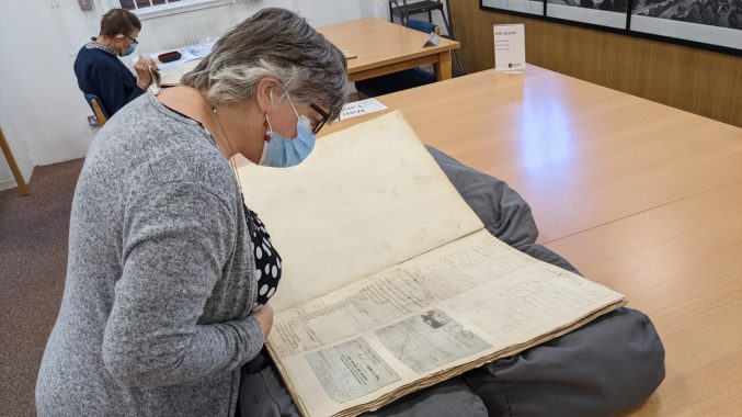 A woman looking at a large volume in Bristol Archives searchroom