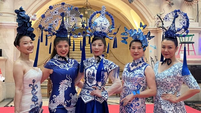 Five women dressed in extravagant blue and white dresses and head pieces