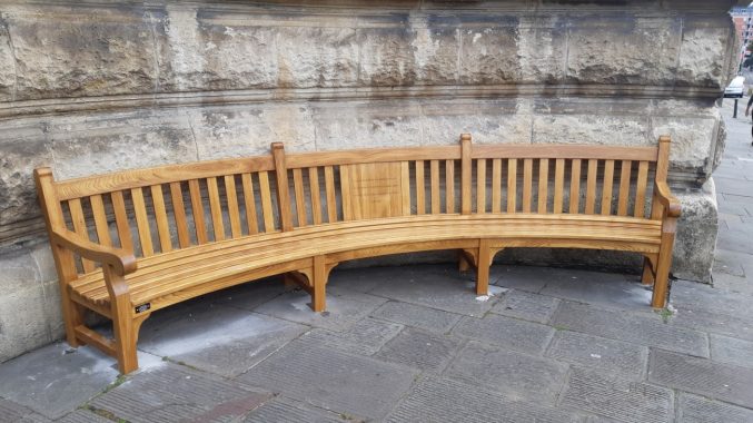 A curved oak bench sitting in an alcove outside Bristol Museum & Art Gallery