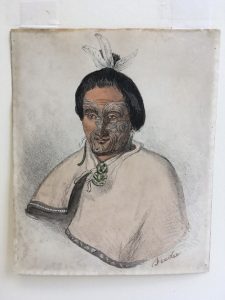 Hand-coloured lithographic print of ‘Feedee’ (Te Whiti), wears feathers tied around his bun and markings on his face.