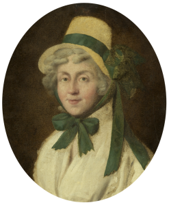 An oil painting of Hannah More in an oval shaped frame. She wears a straw hat with a green ribbon and a white, long sleeved blouse with a matching green ribbon tied in a bow around her neck. She has grey, short locks and a pale complexion.