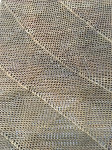A close up of a bag made of looped and netted vegetable fibre with diagonal stripes woven into the body.