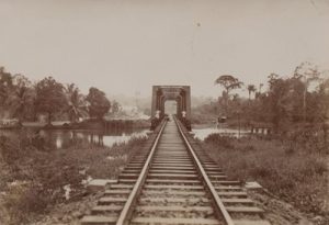 Railway tracks going off into the distance where it meets a bridge over the water.