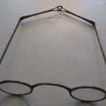 This shows O'Brien's spectacles, which are very large, and made from dark, thin metal with real glass in the lenses. They are photographed from above, leaning slightly to the left.