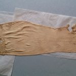 This shows O'Brien's stocking, which is laid flat with the heel facing to the right. They are a dark cream colour and look yellowed with age. They have obviously been used, as they are covered with darning repairs.