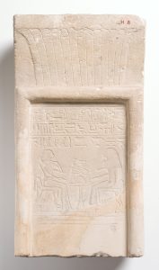 Ancient Egyptian pale coloured stone with hieroglyphics carved into it.