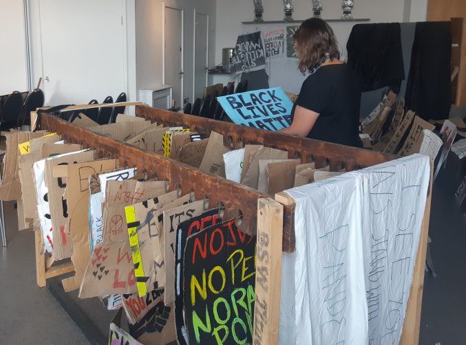 paper conservator ellie inspects a placard next to a rack of blm placards