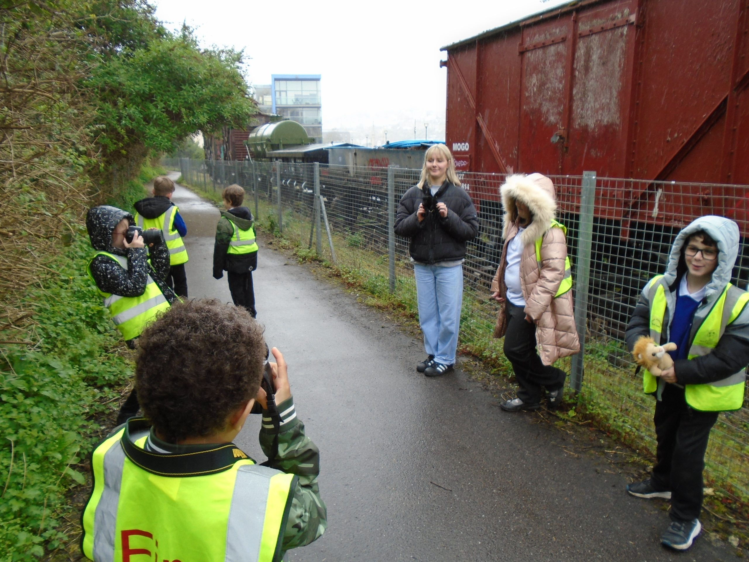 Primary school children taking photos on Bristol harbourside with professional cameras. Railway sidings in background