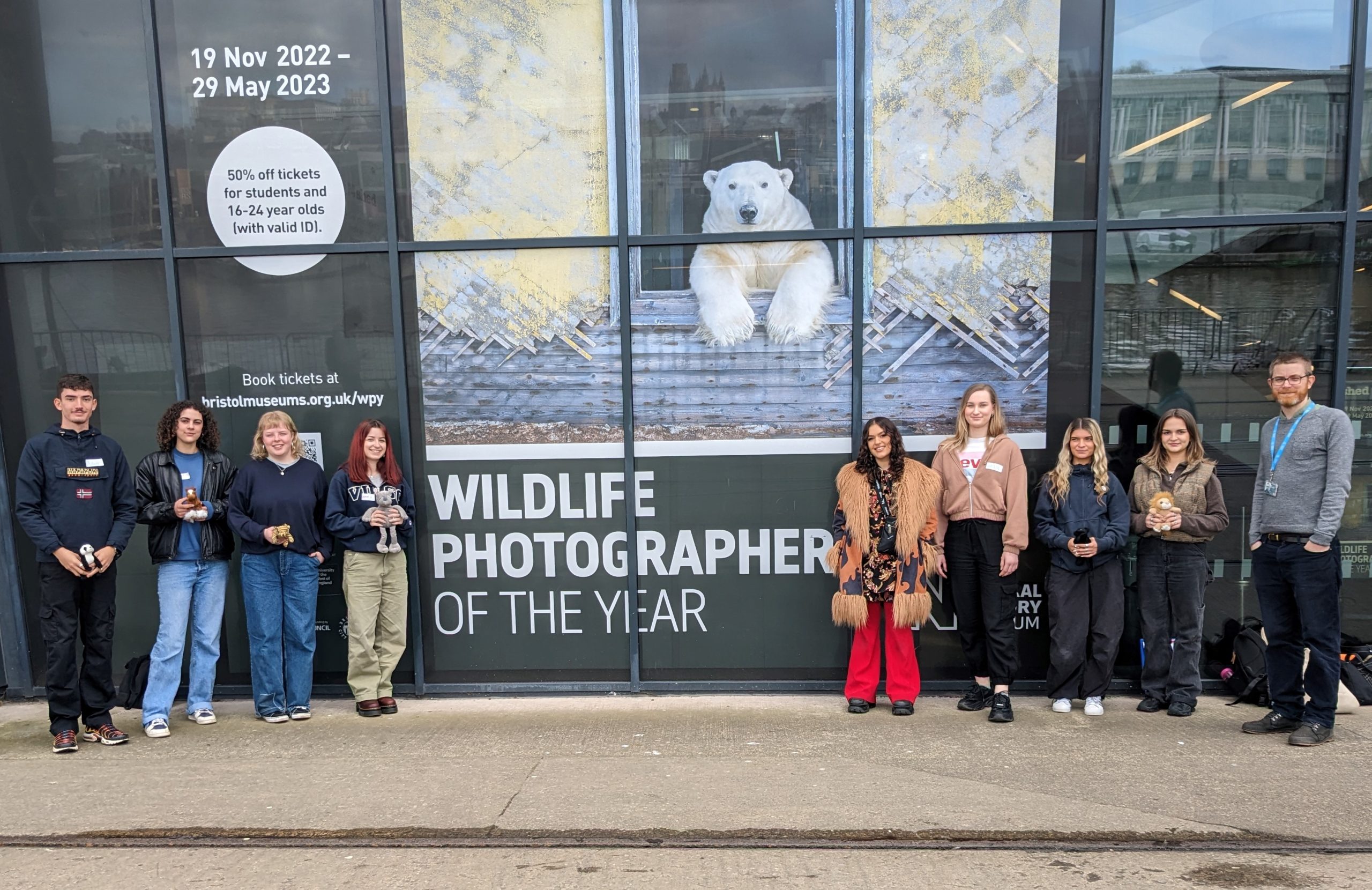 Group of university students outside the M Shed museum with a member of the Museums Learning team. Image of polar bear in background