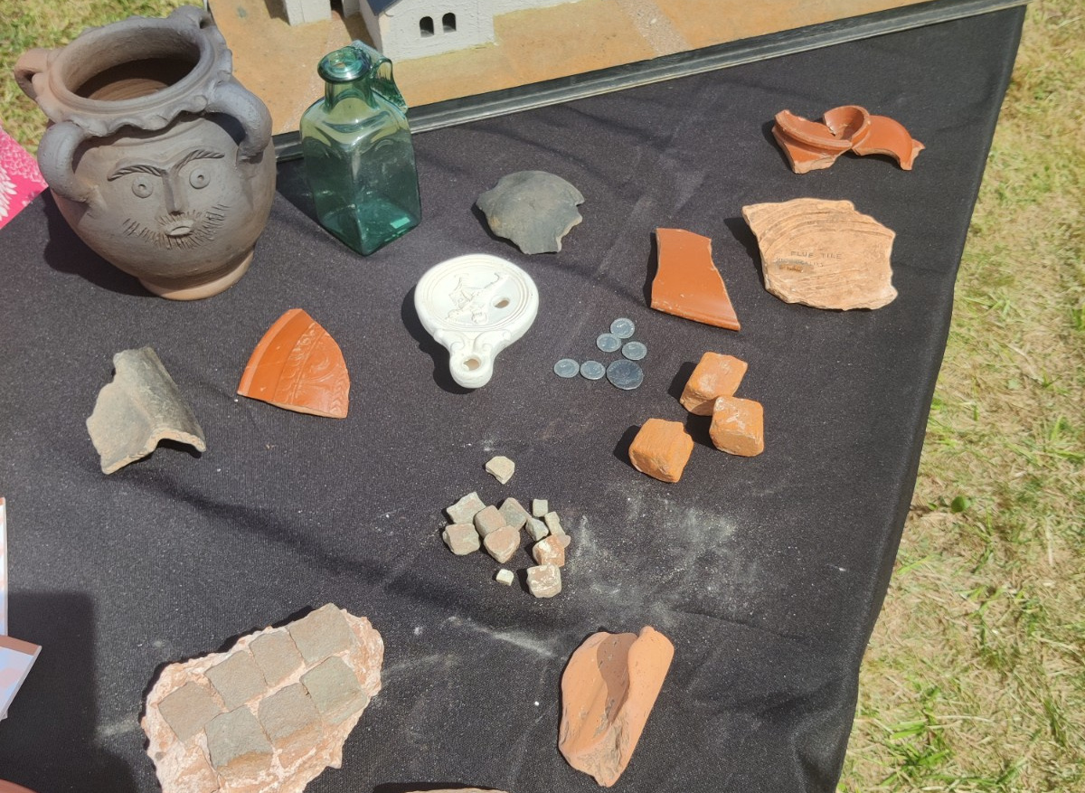 items of pottery and coins on a black sheet on the ground at Kings Weston Roman Villa