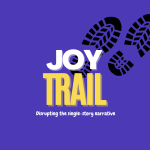White and yellow JOY Trail logo on dark blue background. Slogan reads "Disrupting the single-story narrative". Black shoeprints sit behind the writing on the top right.