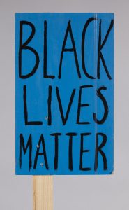 a blue placard with black writing that says 'black lives matter'