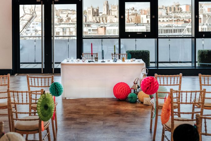 a table and chairs set up for a wedding ceremony with a view of Bristol from a balcony behind