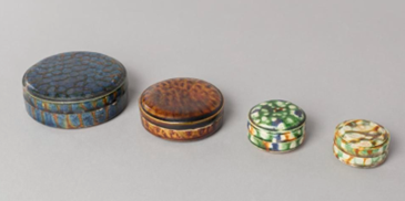 Four small boxes descending in size, from largest on the left to smallest on the right. They are in mottled glazes of black, brown, green and cream. 