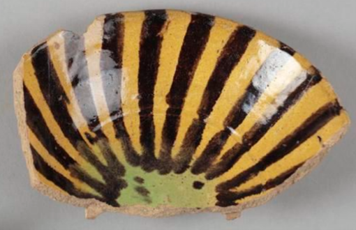 A fragment of ceramic in a brown striped glaze, with yellow and green tones underneath. 
