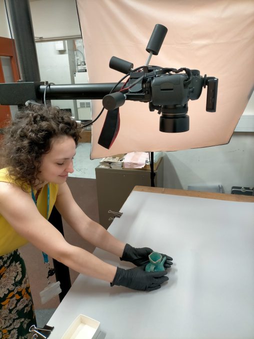 A woman placing a blue glazed bowl onto a table, underneath a mounted camera.