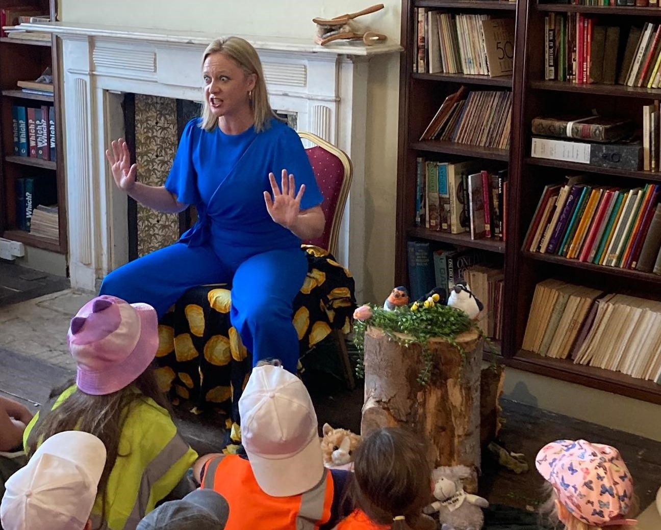 a teacher reads a book to a group of young children seated on the floor