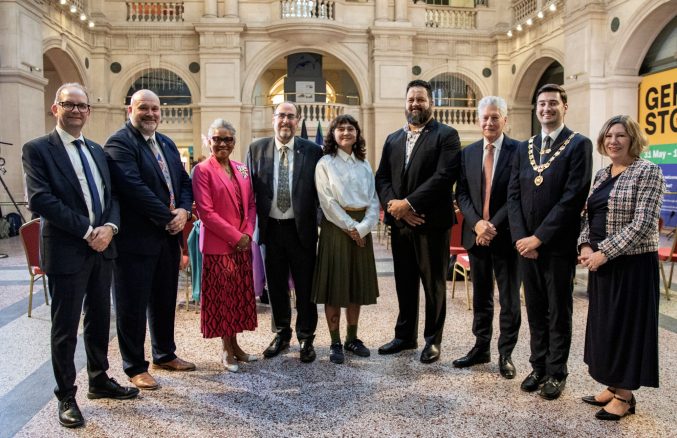 nine people stand in the rear hall of Bristol Museum posing for a photo