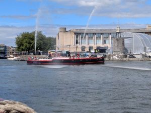 a historic fireboat shoots water cannons in a harbour