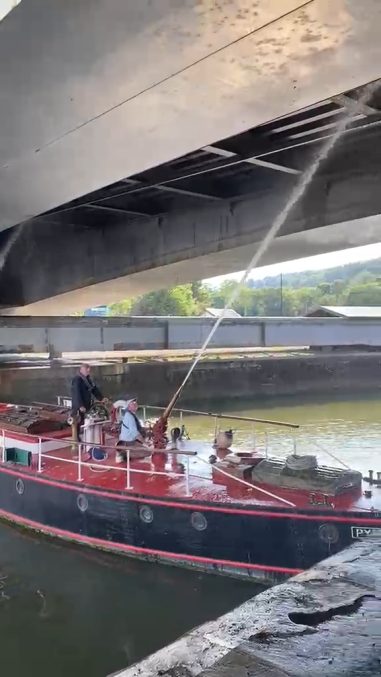 a fireboat shoots water cannons onto the underneath of a bridge from the water