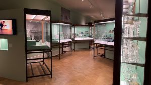 colourful glass objects sit in display cases in a green gallery