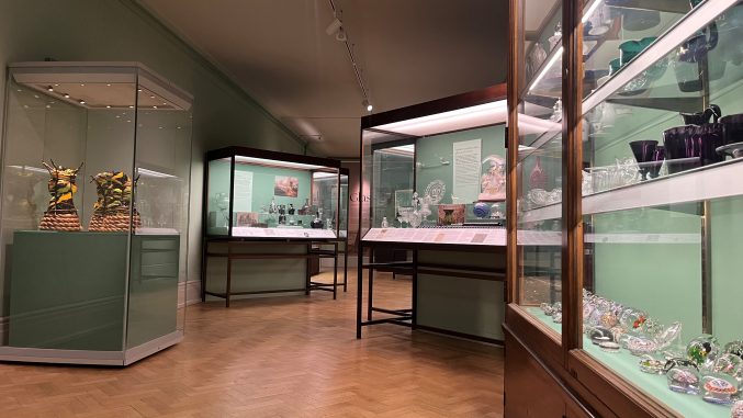 display cases filled with glass objects in a green gallery