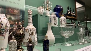 colourful glass objects sit in a display case in a green gallery