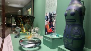 colourful glass objects sit in a display case in a green gallery